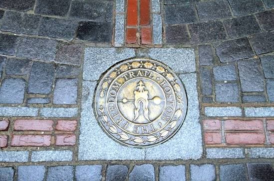 A bronze Freedom Trail medallion set into the cobblestones, reading “The Freedom Trail · Boston”